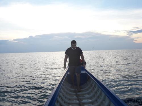 a man standing in a boat in the water at ST 63 Home Stay & Tour Kampong Khleang in Kâmpóng Khleăng