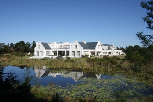 a large white house with a pond in front of it at Buffelsdam Country House in The Crags
