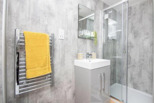 a bathroom with a sink and a shower with a yellow towel at The Nook in Inverness
