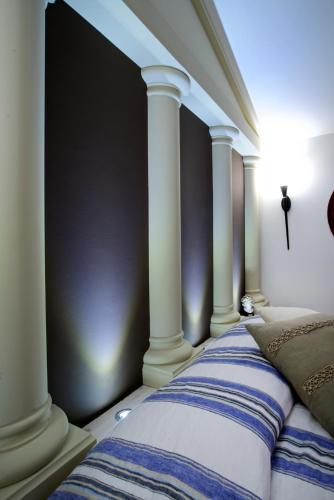 a bed with white columns in a room at Design Suite Tirano in Tirano
