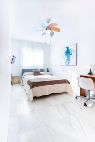 a white bedroom with a bed and a ceiling fan at Piso encantador junto al mar, relax, tranquilidad in Torre del Mar