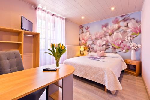 1 dormitorio con 1 cama y una pintura de flores en Le P'tit Bonheur, en Chilly-sur-Salins