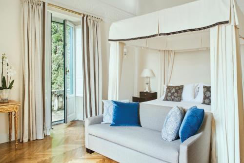 a bedroom with a bed and a couch with blue pillows at Grand Hotel Timeo, A Belmond Hotel, Taormina in Taormina