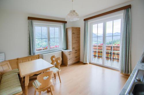 a dining room with a table and chairs and windows at Gästehaus Berger - Priglhof in Treffen