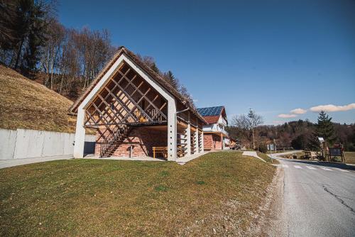a building with a thatched roof on the side of a road at Farm stay Žurej in Šentjur