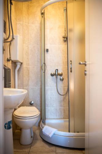 a bathroom with a shower with a toilet and a sink at Garni Hotel Lotos in Niš