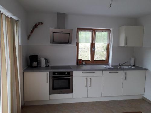 a kitchen with white cabinets and a stove and a window at Haus Berglust Wallgau in Wallgau