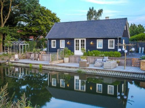 una pequeña casa azul con un reflejo en el agua en Gorgeous Riverside Chalet in Cothen, en Cothen