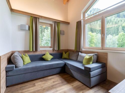 a living room with a blue couch and windows at Chalet in Saalbach near Ski Slopes in Saalbach-Hinterglemm