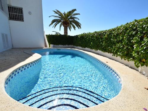a swimming pool in front of a house with a palm tree at Belvilla by OYO Casa Patricia in Altea la Vieja
