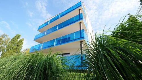 a tall building with blue windows and some grass at Aquarius Santorini in Boszkowo