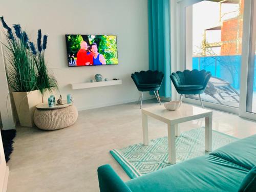 a living room with a couch and a tv on a wall at Aquarius Santorini in Boszkowo