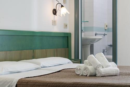 a bedroom with a bed with towels and a sink at Esedra Hotel in Rimini