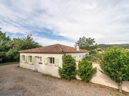 Félines-MinervoisにあるBeautiful villa with spa and heated poolの緑の窓と茂みのある白い家