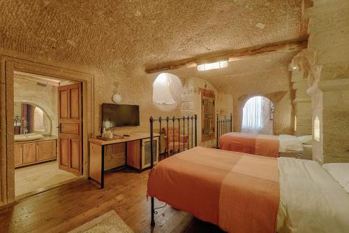a large bedroom with two beds and a television at Taru Cave Suites in Urgup