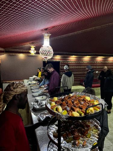 a group of people standing around a buffet line with food at Wadi Rum Desert Adventures in Wadi Rum
