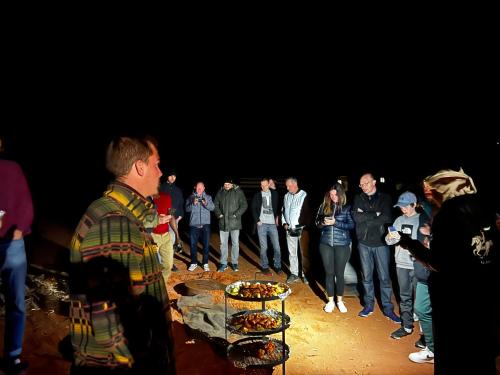 a group of people standing around a table with food at Wadi Rum Desert Adventures in Wadi Rum