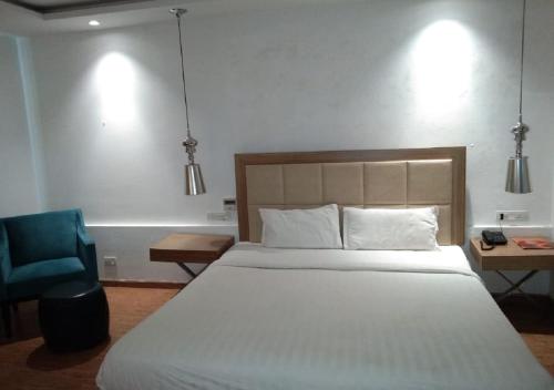 a bedroom with a large bed and a blue chair at HOTEL AMORA - Rajnandgaon in Rāj Nāndgaon