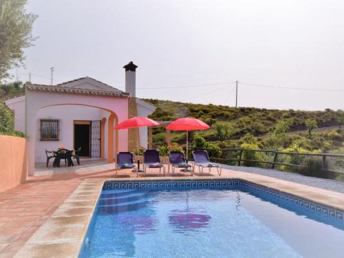 uma casa com piscina com dois guarda-sóis em Belvilla by OYO Casa Guzm n em Árchez