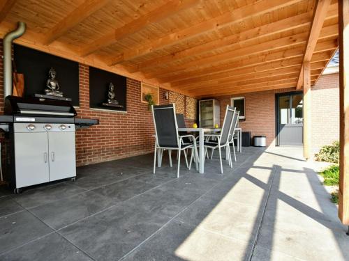 a patio with a table and chairs under a wooden ceiling at Tranquil Group Retreat in Nature in Megchelen