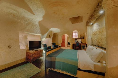 a bedroom with a bed and a tv in it at Taru Cave Suites in Urgup