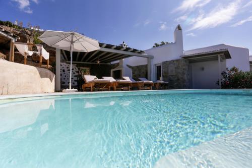 a large swimming pool with chairs and an umbrella at ΑΙΩΡΑ in Mikonos