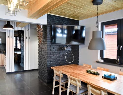 a dining room with a wooden table and a tv on a brick wall at Chata na Czarnym Groniu in Korbielów