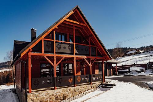 a wooden building with glass windows and snow on the ground at Chata na Czarnym Groniu in Korbielów