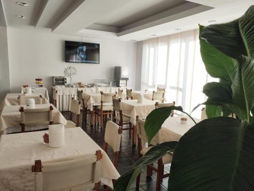 a restaurant with white tables and chairs and a plant at Hotel Galant in Venaria Reale