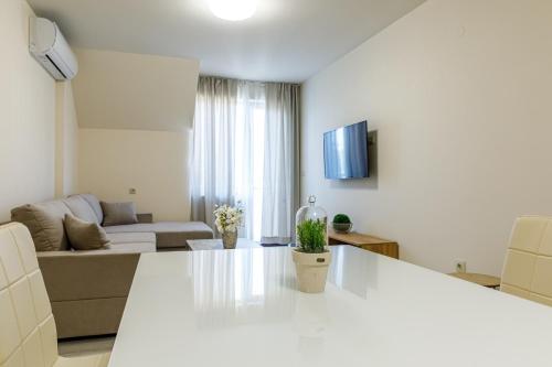 a white living room with a couch and a table at Баня Аква Ризорт in Banya
