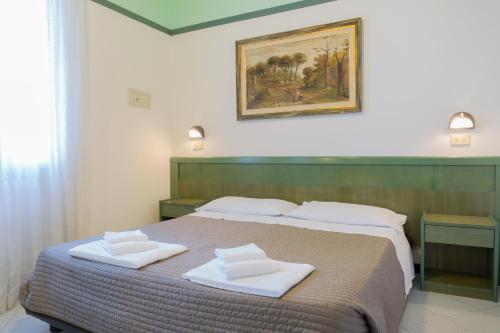 a bedroom with a bed with two white towels on it at Esedra Hotel in Rimini
