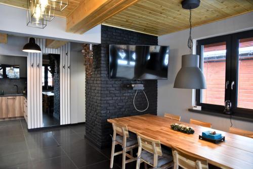 a dining room with a wooden table and a television on a wall at Chata na Czarnym Groniu in Korbielów