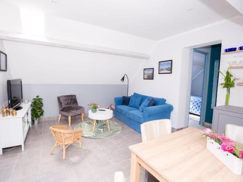 een woonkamer met een blauwe bank en een tafel bij Superb holiday home near the beach in Quinéville
