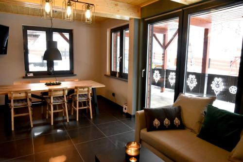 a living room with a couch and a table and windows at Chata na Czarnym Groniu in Korbielów
