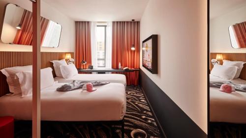 a hotel room with two beds and a mirror at Mama Shelter Paris La Défense in Puteaux