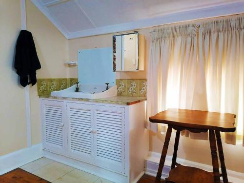 a bathroom with a sink and a wooden table at BillsBest Whaleback Cottage in Ramsgate