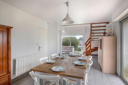 une salle à manger avec une table en bois et des chaises blanches dans l'établissement Vacances pour 6 à 400m de la plage à Sarzeau, à Sarzeau