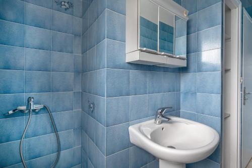 ein blau gefliestes Bad mit einem Waschbecken und einer Dusche in der Unterkunft Vacances pour 6 à 400m de la plage à Sarzeau in Sarzeau