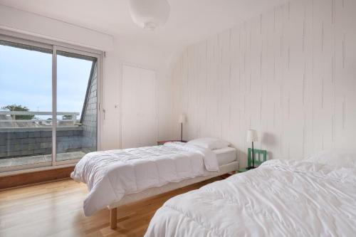 ein weißes Schlafzimmer mit zwei Betten und einem großen Fenster in der Unterkunft Vacances pour 6 à 400m de la plage à Sarzeau in Sarzeau