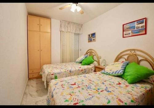1 dormitorio con 2 camas y almohadas verdes en Apartamento la isla, en San Juan de los Terreros