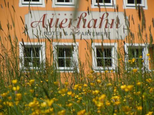 a building with a sign in front of a field of flowers at Hotel & Appartement Auerhahn in Obertauern