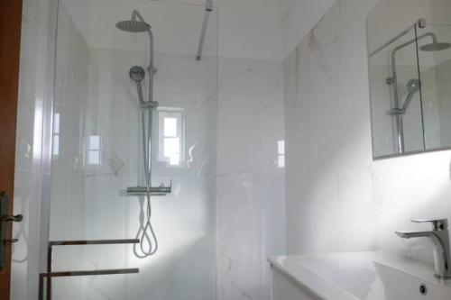 uma casa de banho branca com um chuveiro e um lavatório. em Encosta das Oliveiras 49D em Vilamoura