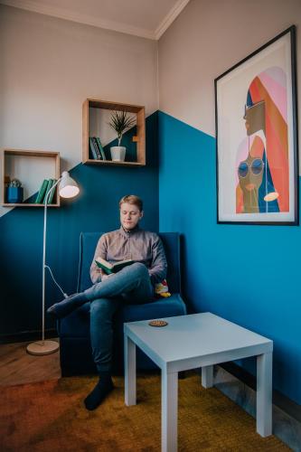 a man sitting on a chair reading a book at People Hostel in Bishkek