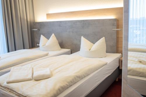 two beds with white sheets and pillows on them at Landhotel Stüer in Altenberge