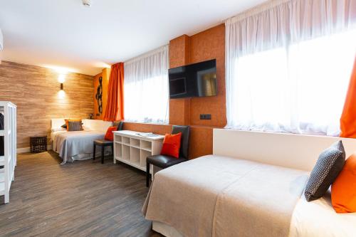 a hotel room with two beds and a desk at Fly Rooms Madrid Airport in Madrid