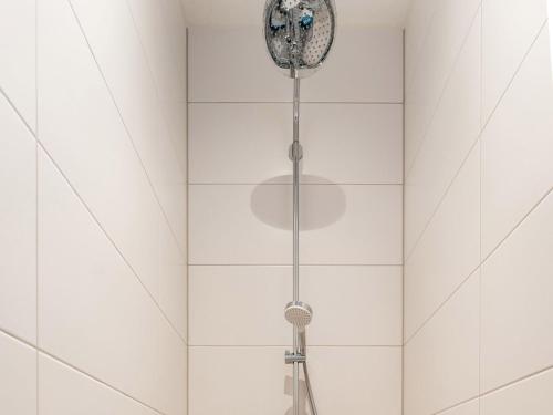 a shower with a shower head in a white bathroom at Alluring Holiday Home in De Koog Texel with Infrared Sauna in Westermient