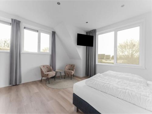 a white bedroom with a bed and two chairs at Holiday Home in De Koog near Forest in Westermient