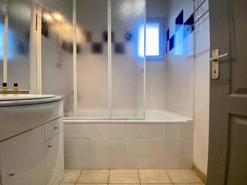 La salle de bains blanche est pourvue d'une douche et d'une baignoire. dans l'établissement Le 24 Février - PARKING & PISCINE - VUE CITÉ MÉDIÉVALE, à Carcassonne