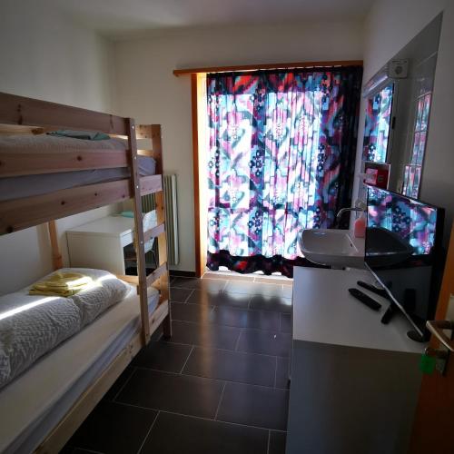 een slaapkamer met een stapelbed, een televisie en een raam bij Ferienwohnung Crea in Adelboden