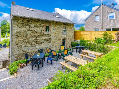 un patio avec des tables et des chaises en face d'un bâtiment dans l'établissement Spacious Cottage in Harz with Garden and Barbecue, à Harzé